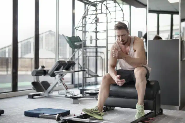 Atleta agotado por la fatiga muscular en el gimnasio, factor clave en los calambres en Hyrox